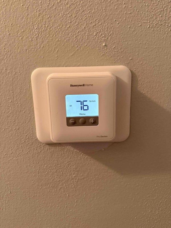 Responded to service call for non-functioning air conditioning system and thermostat. Upon inspection, diagnosed faulty thermostat as root cause of system failure. Removed defective unit and installed new Honeywell Home Pro-Series digital thermostat, ensuring proper wiring connections and system configuration. Verified system operation with display showing proper temperature reading of 76°F and confirmed all control functions including heating/cooling modes and fan settings operating correctly.