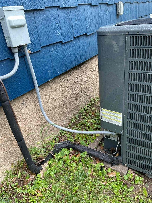 Returned to address no cooling complaint on five-year-old Goodman unit following initial service visit. Contacted technical support to diagnose intermittent failure and assessed refrigerant system for potential leaks or charging issues. Documented outdoor condenser unit condition with photos showing vegetation growth around equipment and verified electrical connections at disconnect box.