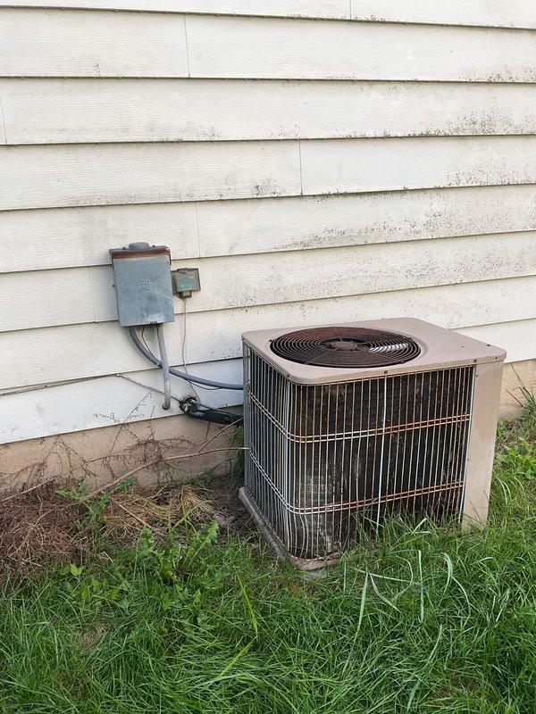 Responded to service call for air conditioning system not operating at vacant property. Upon arrival, accessed unit using provided lockbox code and performed diagnostic assessment of outdoor condenser unit and indoor thermostat controls. Inspected outdoor condensing unit positioned against exterior wall, verified electrical connections at disconnect box, and examined conduit routing from unit to wall-mounted disconnect. Checked indoor Honeywell digital thermostat for proper settings and functionality. System evaluated and photographed for documentation purposes.