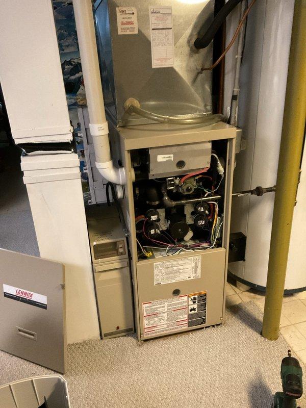 Performed comprehensive clean and check service on 2003 Lennox furnace and air conditioning system. Inspected internal blower assembly, electrical connections, and control mechanisms on furnace unit with access panel removed for thorough examination. Evaluated outdoor condenser unit, fan operation, and electrical disconnect components, confirming proper system function on both heating and cooling equipment.