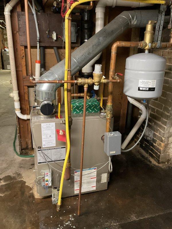 Responded to service call for leaking backflow preventer and automatic fill valve on residential boiler system. Upon inspection, confirmed active leaks at both components with visible water accumulation on basement floor. Removed and replaced failed backflow preventer and fill valve assembly with new components. Reconnected all copper piping connections and verified proper sealing at brass fittings. Adjusted boiler operating pressure to manufacturer specifications and tested system operation. Confirmed no leaks present and proper fill valve function upon completion.