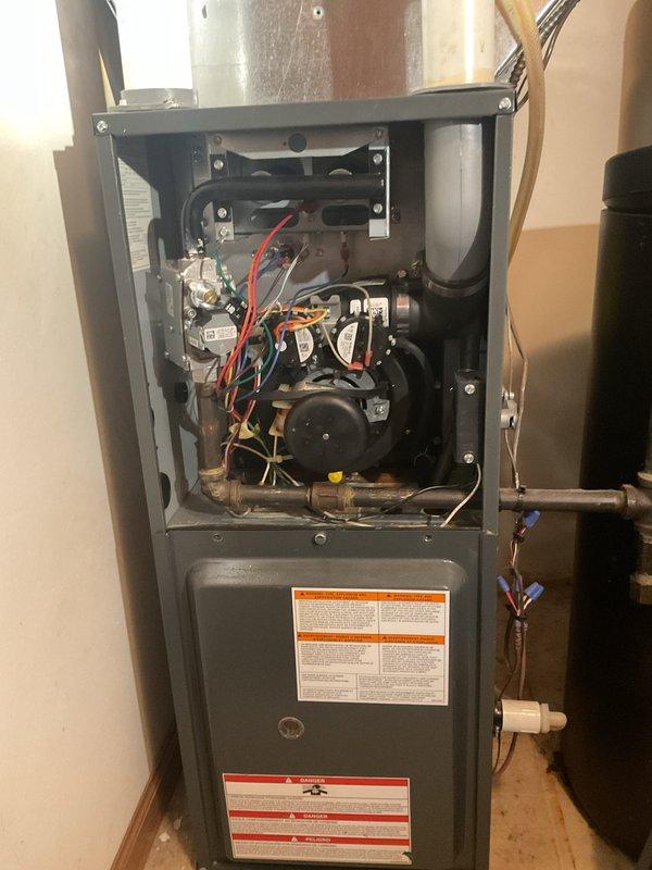 Completed comprehensive furnace clean and check maintenance service on residential forced-air heating system. Removed access panels to inspect internal components including blower motor assembly, gas valve, control boards, electrical connections, and wiring harness. All colored wiring connections were verified secure with no signs of deterioration or loose terminals. Blower motor and housing inspected and found in good operational condition. Gas line connections checked for proper installation and safety compliance. Unit exterior and interior components showed no visible signs of excessive wear, damage, or safety concerns at time of service.