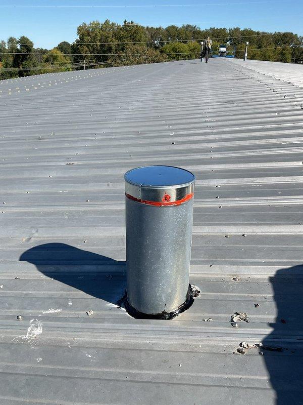 Completed rooftop ventilation system repair by installing new metal vent pipe with proper flashing and weatherproof boot collar on ribbed metal roof. Replaced corrugated vent section and secured all connections to ensure proper exhaust venting and prevent water intrusion. System tested and verified operational with all components properly sealed and fastened.