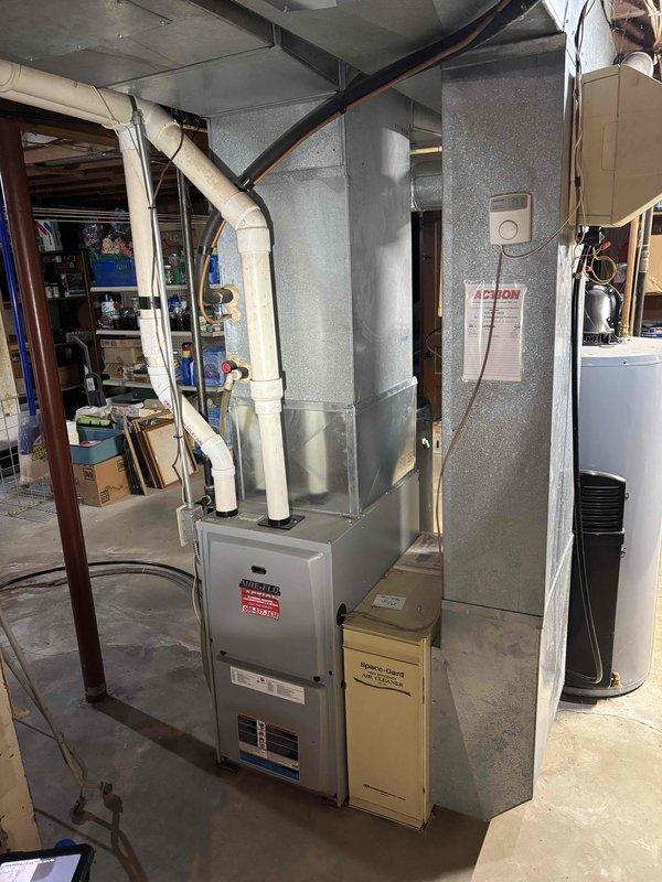 Responded to no heat call on residential furnace system. Upon arrival, inspected aging HVAC equipment in basement installation with extensive ductwork configuration. Performed diagnostic evaluation of gray metal furnace unit and associated air handler system. Measured clearances and documented equipment specifications including filter compartment marked with replacement filter information. System appeared to have standard wear consistent with age. Completed troubleshooting procedures and restored heat operation to residence.