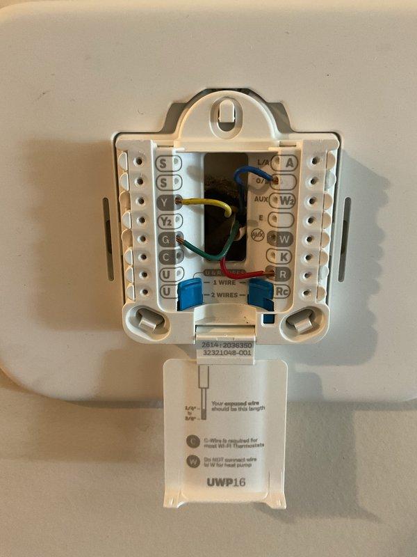 Responded to no-heat call on water source heat pump system following previous technician's diagnosis of suspected control board failure. Inspected electrical connections at terminal block and transformer assembly, verifying wire terminations at numbered terminals and thermostat base plate. Documented wiring configuration including R, W, Y, G, and AUX terminals on UWP16 control, with all low-voltage connections intact at both unit and wall-mounted thermostat locations.