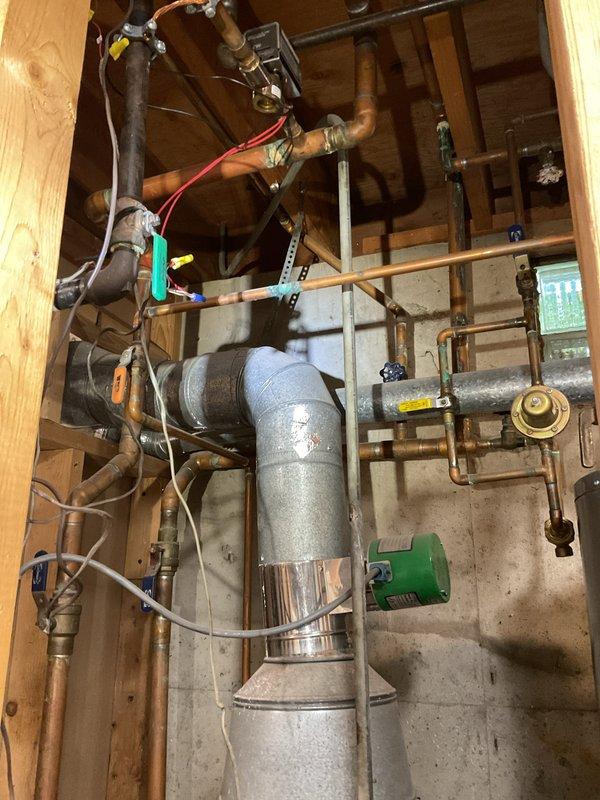 Responded to a no-heat call on a gas-fired boiler system (installed approx. 2011) serving the whole house. Inspected the boiler, flue venting, control components, and associated hydronic piping in the mechanical room, and noted no visible leaks, frost, or ice; some copper fittings showed oxidation and the boiler base area had debris and residue. Documented system conditions with photos.