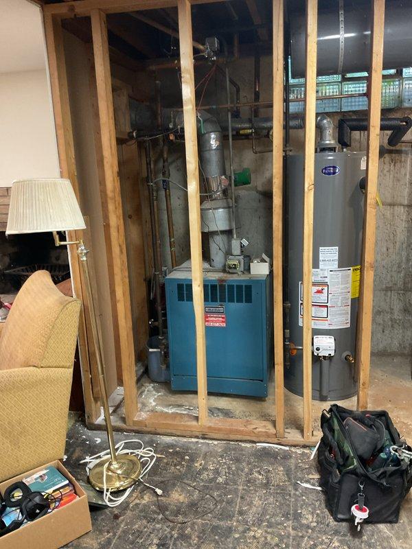 Responded to a no-heat call on a gas-fired boiler system (installed approx. 2011) serving the whole house. Inspected the boiler, flue venting, control components, and associated hydronic piping in the mechanical room, and noted no visible leaks, frost, or ice; some copper fittings showed oxidation and the boiler base area had debris and residue. Documented system conditions with photos.
