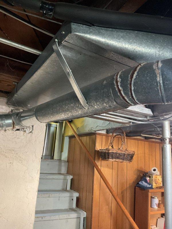 Performed a complete heating system tune-up on an 11-year-old Carrier upright furnace, inspecting the cabinet, flue venting, and supply ductwork for proper connections and condition. Noted surface corrosion and weathering on sections of the galvanized round ductwork and flue, which should be monitored for future sealing or replacement. The furnace was operated through a heating cycle to verify proper function, and the unit is in operational condition following the maintenance.
