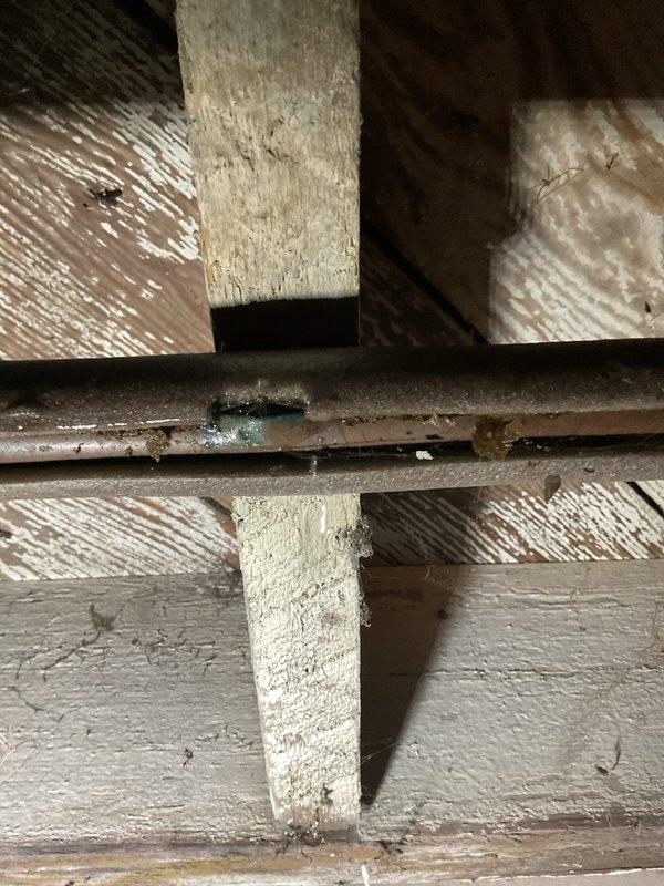 Diagnosed a no-heat condition on a gas-fired boiler and found the supply valve closed; opening it revealed three separate active water leaks from burst, corroded piping in the overhead and underfloor runs, including a pinhole failure with copper corrosion at a pipe junction. Repairs could not be completed during this visit, and the boiler remains out of service pending approval to proceed with piping repairs.