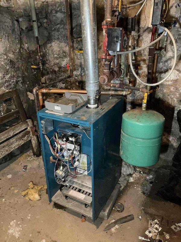 Diagnosed a no-heat condition on a gas-fired boiler and found the supply valve closed; opening it revealed three separate active water leaks from burst, corroded piping in the overhead and underfloor runs, including a pinhole failure with copper corrosion at a pipe junction. Repairs could not be completed during this visit, and the boiler remains out of service pending approval to proceed with piping repairs.