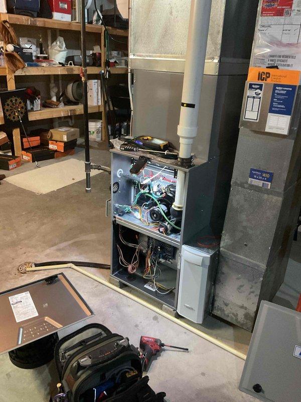 Performed seasonal maintenance on an 11-year-old Heil gas-fired condensing furnace, including removal of the access panel, cleaning of the blower assembly and internal components, and inspection of wiring, the control board, and the PVC vent and condensate drain line. Verified operation with a digital test instrument and confirmed no visible rust, frost, or damage on the furnace, ductwork plenum, or the attached Aprilaire humidifier; unit was reassembled and left operating normally.