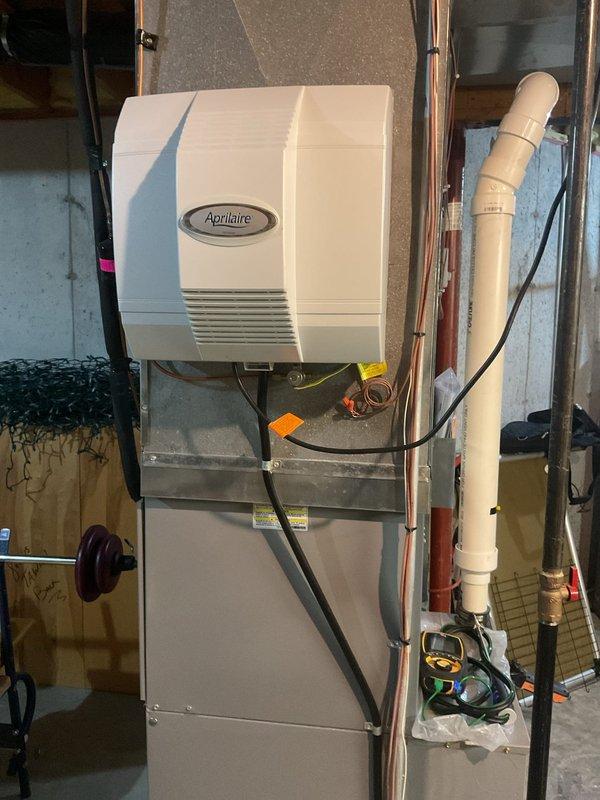 Performed seasonal maintenance on an 11-year-old Heil gas-fired condensing furnace, including removal of the access panel, cleaning of the blower assembly and internal components, and inspection of wiring, the control board, and the PVC vent and condensate drain line. Verified operation with a digital test instrument and confirmed no visible rust, frost, or damage on the furnace, ductwork plenum, or the attached Aprilaire humidifier; unit was reassembled and left operating normally.