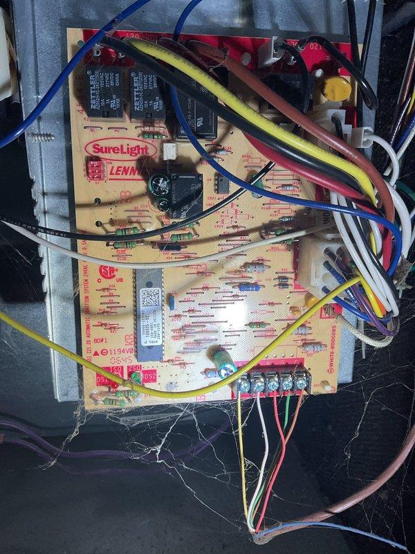 Responded to a call for a furnace blower that continued running after the call for heat ended. Inspected the Lennox gas furnace and removed the lower access panel to evaluate the SureLight integrated control board, wiring, and thermostat circuit connections. Found accumulated dust and cobwebs around the control board and low-voltage terminals, which can interfere with fan control operation, and verified the thermostat circuit as the likely source of the continuous fan condition.
