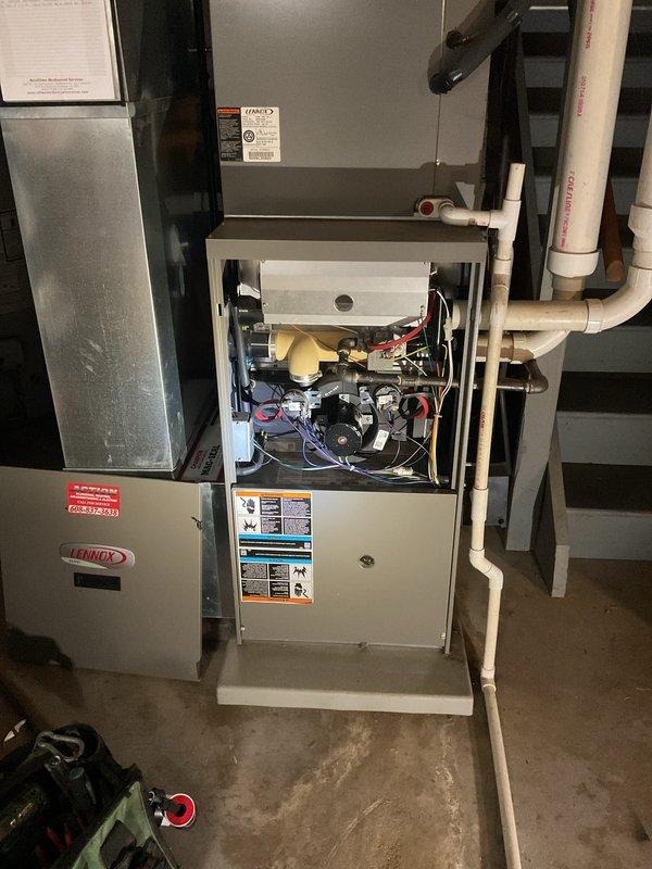 Responded to a call for a furnace blower that continued running after the call for heat ended. Inspected the Lennox gas furnace and removed the lower access panel to evaluate the SureLight integrated control board, wiring, and thermostat circuit connections. Found accumulated dust and cobwebs around the control board and low-voltage terminals, which can interfere with fan control operation, and verified the thermostat circuit as the likely source of the continuous fan condition.