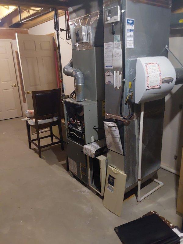 Performed furnace retrofit to address heating failure in residential basement. Installed new gray furnace unit with digital control panel and connected existing ductwork system with proper sealing. Added humidifier/air purifier attachment to improve indoor air quality.