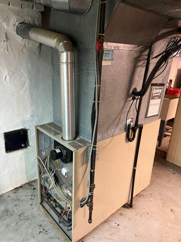 Completed comprehensive inspection of existing HVAC system in basement utility room. Documented current installation showing furnace with exposed control panel adjacent to water heater with associated copper piping and ductwork. Assessment focused on metal exhaust configuration, electrical connections, and overall system integration within the mechanical space.