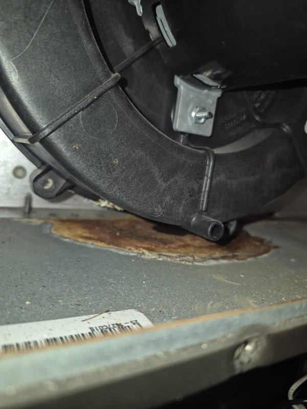 Sealed inducer motor assembly after identifying rust/corrosion on the housing base. Performed combustion analysis using Bacharach Fyrite INTECH analyzer, confirming optimal system performance with readings of 7.3% O2, 16ppm CO, 98.2% efficiency, and 7.7% CO2.