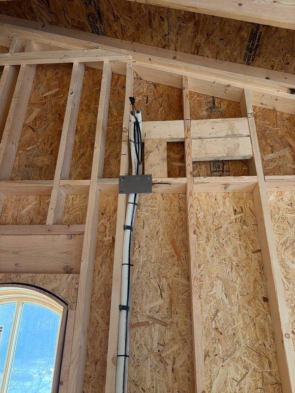 Completed rough-in installation of line sets for mini-split system. Installed copper lines through framed walls with proper penetration points. System components were properly positioned according to specifications with PVC drain line routed through wall cavity for condensate removal.