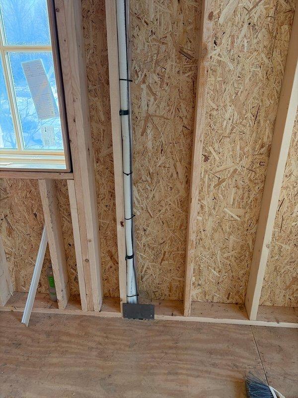 Completed rough-in installation of line sets for mini-split system. Installed copper lines through framed walls with proper penetration points. System components were properly positioned according to specifications with PVC drain line routed through wall cavity for condensate removal.