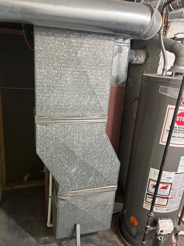 Completed furnace retrofit to replace 45-year-old non-functioning unit with new equipment in basement utility area. Installed modern two-tone furnace with proper PVC venting and connected to existing galvanized ductwork system. System is now operational, resolving the no-heat condition.
