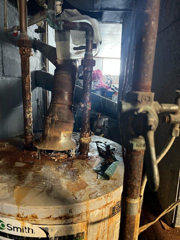 Performed inspection of 30-year-old HVAC system showing extensive deterioration, including severely corroded Smith water heater with rust damage throughout connecting pipes and Cleveland furnace with significant rust staining. System is at end of life cycle with multiple component failures; provided replacement estimate for basic equipment package as requested by customer.