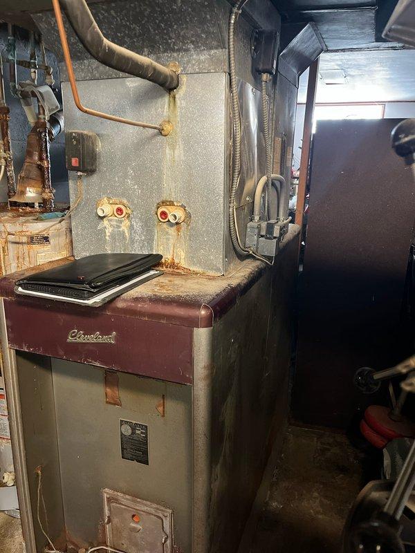 Performed inspection of 30-year-old HVAC system showing extensive deterioration, including severely corroded Smith water heater with rust damage throughout connecting pipes and Cleveland furnace with significant rust staining. System is at end of life cycle with multiple component failures; provided replacement estimate for basic equipment package as requested by customer.