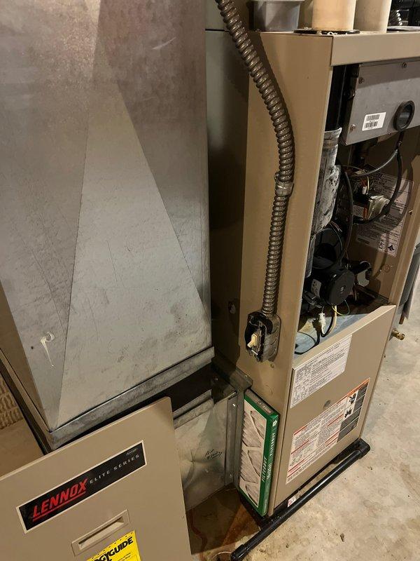 Completed installation of a Lennox Elite Series HVAC system in the utility room, including proper electrical connections and ductwork integration. Observed and documented copper line sets with insulation running along the concrete block wall. Noted potential moisture issue with visible staining near the basement window that may require future attention.