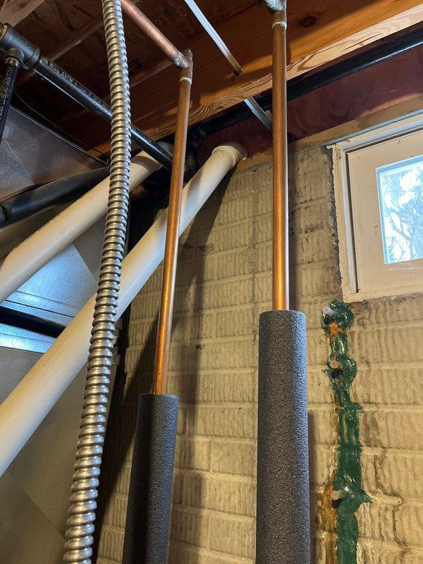 Completed installation of a Lennox Elite Series HVAC system in the utility room, including proper electrical connections and ductwork integration. Observed and documented copper line sets with insulation running along the concrete block wall. Noted potential moisture issue with visible staining near the basement window that may require future attention.