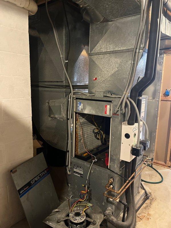 Conducted comprehensive assessment of existing HVAC system in utility area. Documented aging furnace with Spectra components showing signs of normal wear. Examined ductwork configuration, refrigerant lines, and electrical connections for replacement planning. System currently operational but replacement recommended due to age and efficiency concerns.