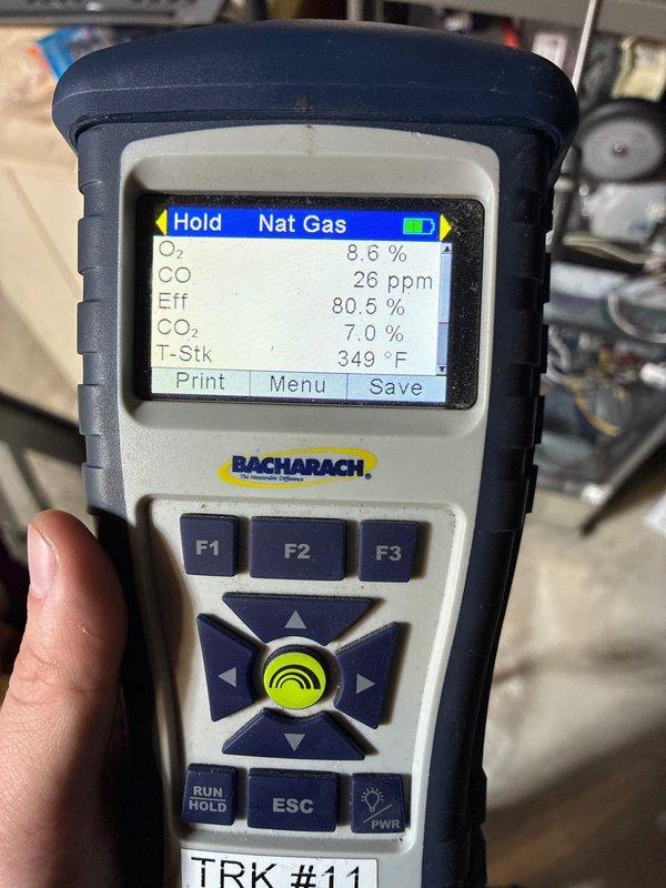 Performed thermostat battery replacement and conducted comprehensive furnace operational check. Analysis with Bacharach gas analyzer showed natural gas combustion readings with O₂ at 8.6%, CO at 26 ppm, efficiency at 80.5%, CO₂ at 7.0%, and stack temperature at 349°F, confirming system is operating within acceptable parameters.