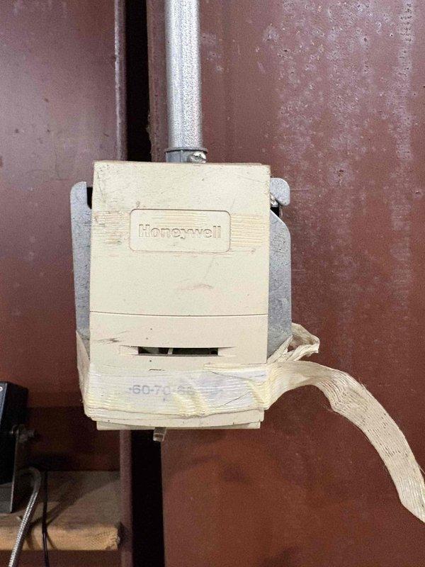 Completed fall maintenance inspection on commercial HVAC system. Examined Honeywell control device showing signs of aging and weathering with adhesive tape around lower portion. Inspected terminal block connections and verified proper wiring configuration with all leads (green, white, red, yellow, and black) securely connected to appropriate terminals.