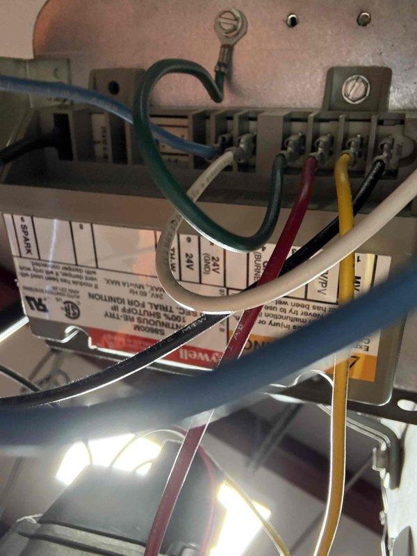 Completed fall maintenance inspection on commercial HVAC system. Examined Honeywell control device showing signs of aging and weathering with adhesive tape around lower portion. Inspected terminal block connections and verified proper wiring configuration with all leads (green, white, red, yellow, and black) securely connected to appropriate terminals.