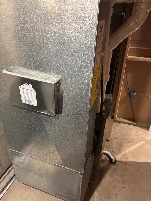 Completed furnace retrofit installation in utility room, replacing existing unit with new metallic HVAC system. Installed proper PVC exhaust ventilation with multiple joints extending upward from the unit, and connected condensate drain line along the furnace side to ensure proper drainage.