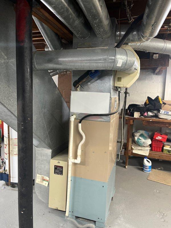 Completed replacement of aging HVAC system in residential basement, including removal of old furnace and installation of new beige/light blue furnace unit with properly connected galvanized ductwork. System was installed with appropriate PVC condensate drainage and all necessary connections to existing distribution network.