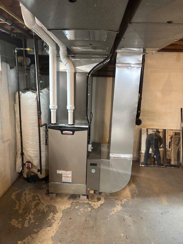 Completed installation of a new Lennox HVAC system in basement utility area, including furnace unit with proper sheet metal ductwork connections and PVC venting pipes. System was integrated with existing plumbing infrastructure, with all components properly secured to concrete block walls and ceiling joists for optimal performance.