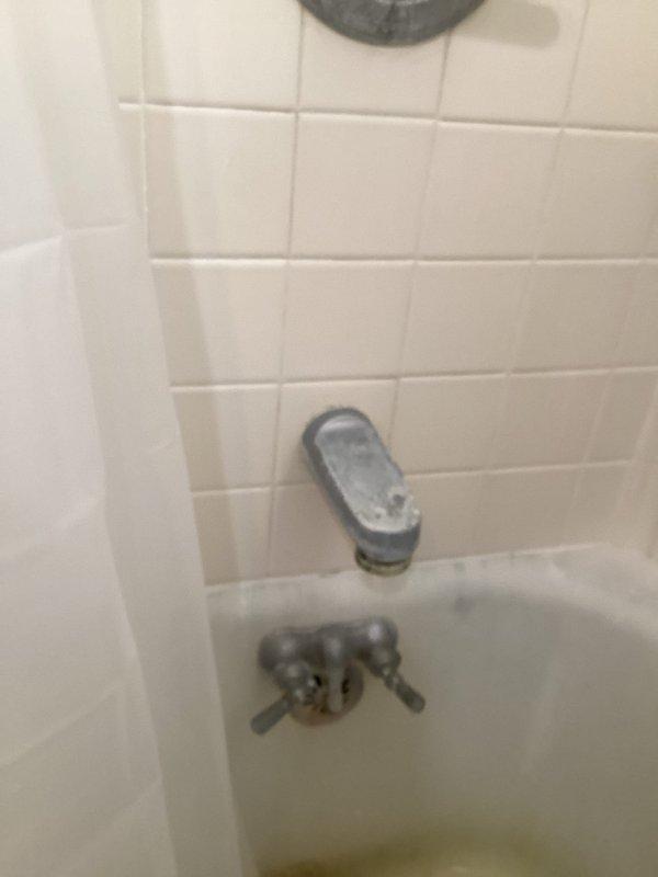 Responded to client request for shower plumbing service regarding water drainage issue. Inspected white bathtub and shower assembly with chrome fixtures showing signs of age and mineral deposits. Resolved drainage problem that was causing water to hold in tub, restoring proper water flow and functionality.