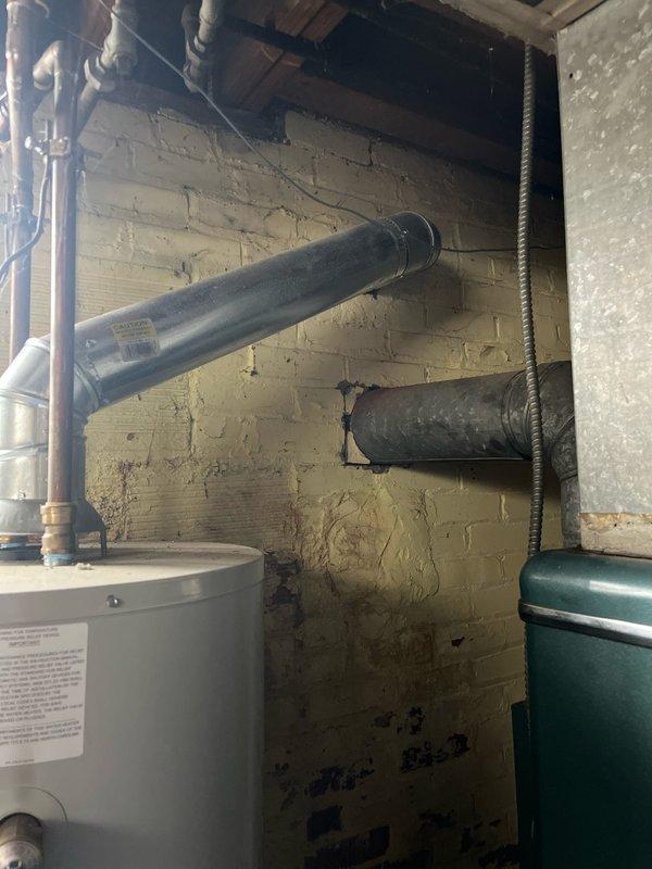 Conducted assessment of aging HVAC system in basement utility area. Recommended replacement with 80% efficient furnace and 13 SEER air conditioning unit. Noted significant dust accumulation on ceiling joists and potential ventilation issues with existing exhaust pipes that would be addressed during installation.