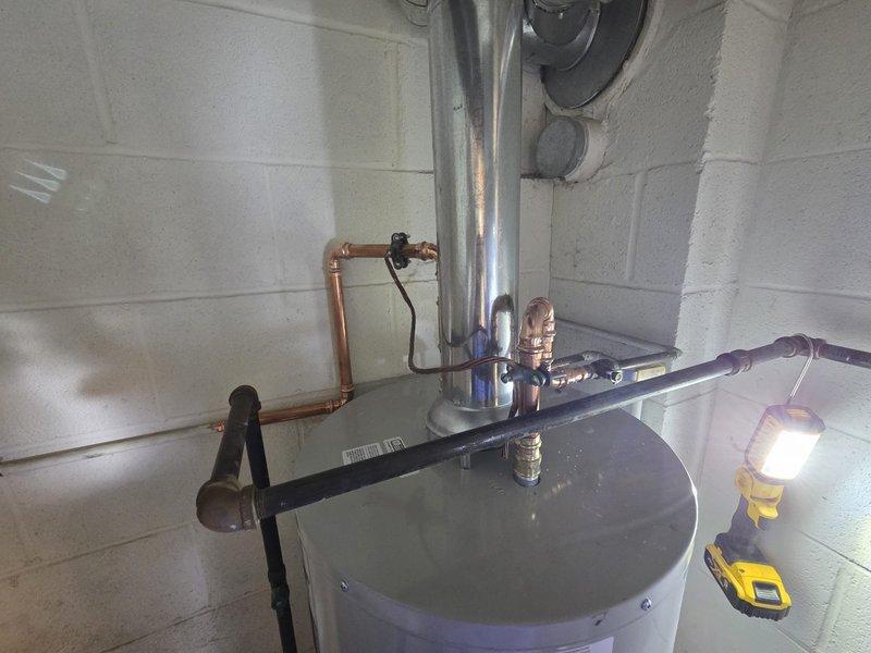 Successfully installed a new commercial tanked water heater in utility room with proper copper pipe connections and fittings, including pressure relief valve. Completed installation of metal flue pipe for proper venting, and ensured all connections were secure with no leaks upon final testing.