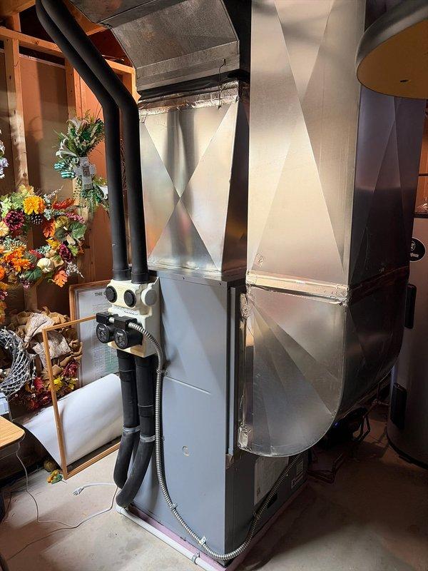 Successfully installed a new geothermal HVAC system in the basement utility room, including proper connection of the furnace unit to existing ductwork and copper piping. System features include insulated flexible ducts for efficient air distribution and a control interface with monitoring gauges, with all components securely mounted and sealed according to manufacturer specifications.