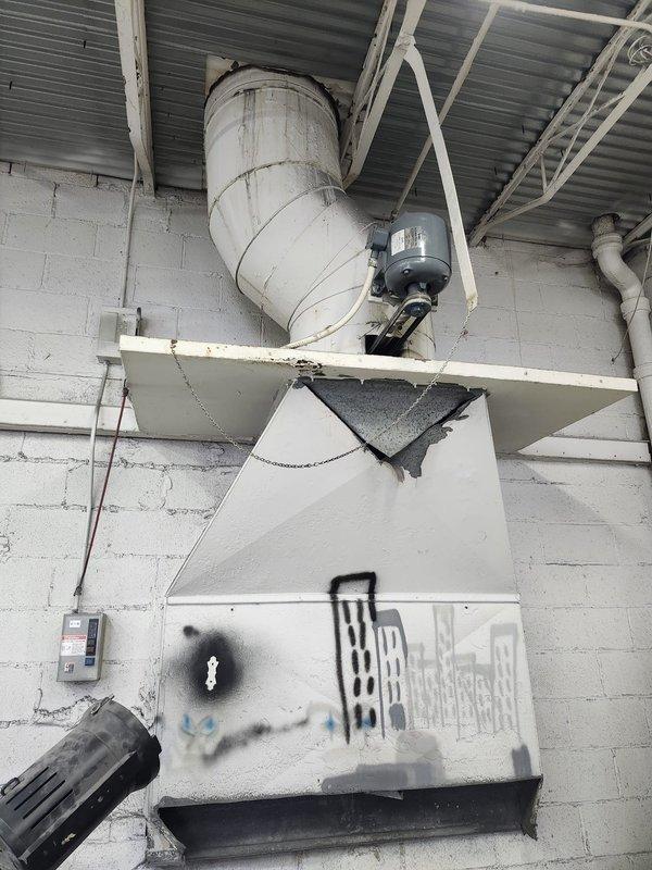 Responded to service call regarding malfunctioning exhaust fan in a commercial facility. Upon inspection, found an aging exhaust ventilation system with significant dust accumulation and deterioration on the fan unit mounted to concrete block wall. Fan motor was non-operational and housing showed considerable wear with debris buildup on blades, requiring complete replacement.