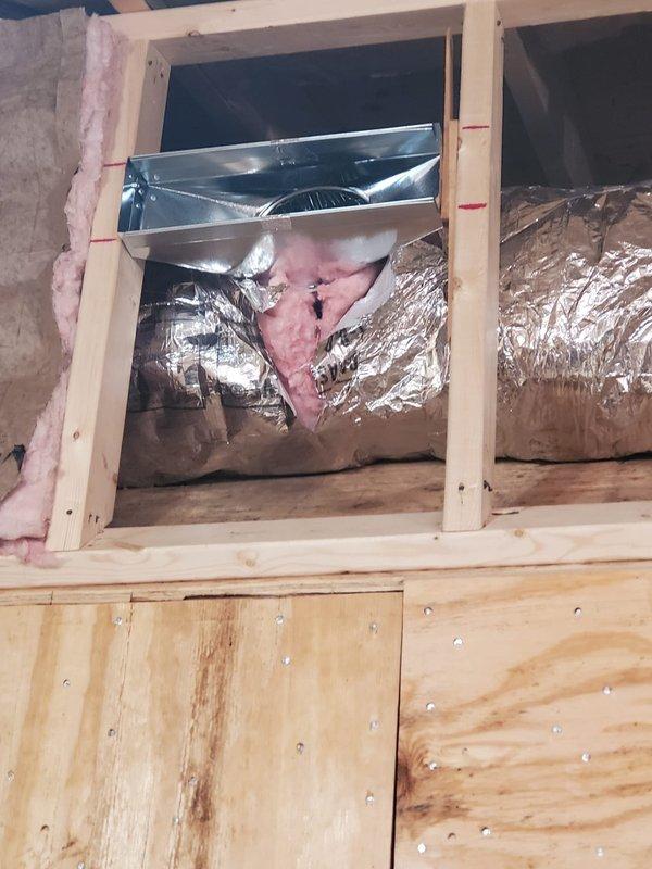 Conducted site inspection of new construction HVAC installation. Verified proper installation of insulated ductwork through framed openings with R13 insulation present, and confirmed appropriate placement of metal register boxes and vent connectors. All components appear correctly installed with proper sealing and insulation prior to drywall installation.