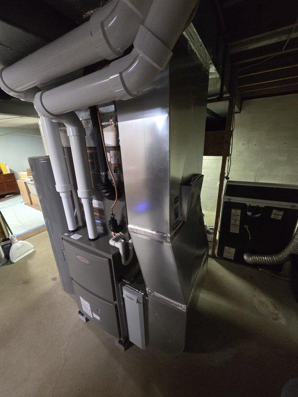 Completed furnace and AC retrofit installation in residential basement. Installed new Rheem system with PVC ventilation pipes, connected to existing ductwork, and ensured proper integration with hot water tank and associated plumbing components. System was tested and verified operational as indicated by control panel indicator light.