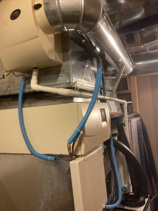 Responded to service callback regarding hot water tank leak. Upon inspection, identified condensate drainage issue from HVAC system with improper routing of blue flexible drain line. Redirected condensate drain line to proper discharge point and secured all connections to eliminate leakage, removing collection bucket that was previously needed.