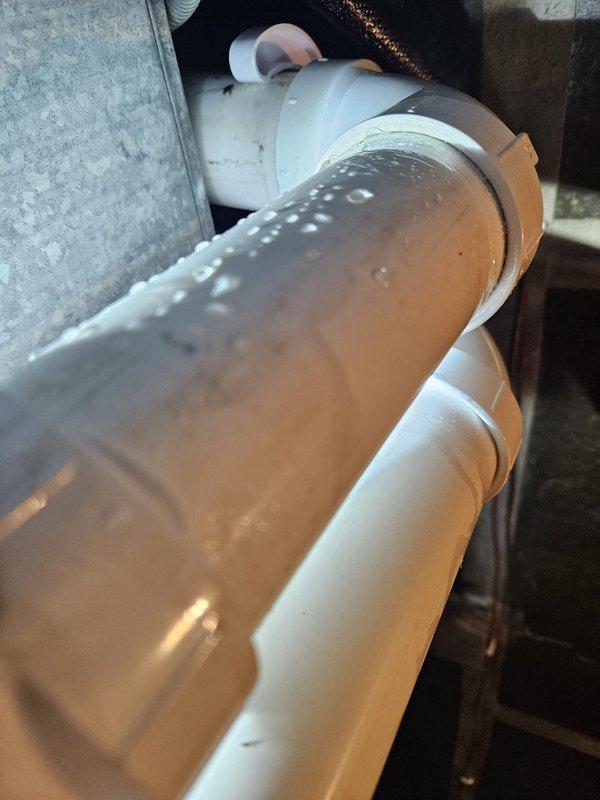 Responded to service call regarding condensation on PVC drain pipes associated with recent heat pump installation. Inspected the affected piping system, which showed significant moisture buildup on exterior surfaces of the white PVC drain lines. Determined this was a residual issue from the original installation that required proper insulation to prevent future condensation problems.