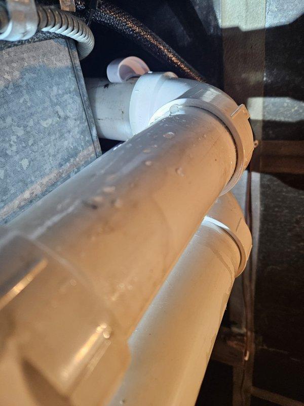 Responded to service call regarding condensation on PVC drain pipes associated with recent heat pump installation. Inspected the affected piping system, which showed significant moisture buildup on exterior surfaces of the white PVC drain lines. Determined this was a residual issue from the original installation that required proper insulation to prevent future condensation problems.