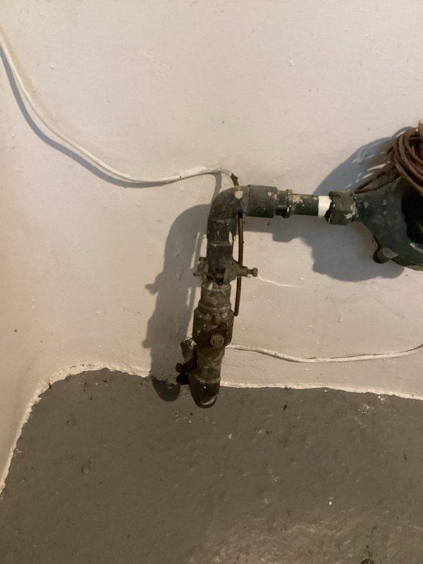 Replaced deteriorated shut-off valve on main water line that showed significant corrosion and mineral buildup. Installation included new valve assembly with proper fittings to connect to existing L-shaped pipe configuration. System was tested for proper operation and verified no leaks at connection points.