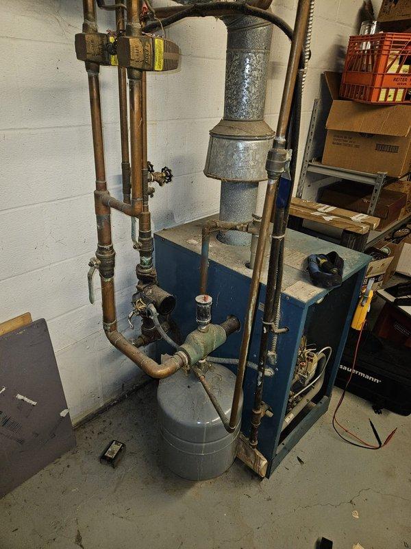 Performed diagnostic assessment on aging boiler system in 1976 home where customer reported furnace not working. Visual inspection revealed older copper piping with oxidation and aging components, including expansion tank and pressure relief valves. System appears to be a standard residential hydronic heating installation requiring further evaluation for proper functionality.