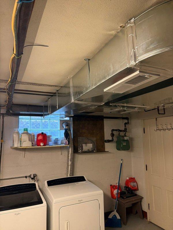 # HVAC Ductwork Reinstallation - Basement Utility Area

Completed comprehensive ductwork reinstallation in residential basement mechanical room. Removed existing galvanized sheet metal ductwork system and reinstalled new horizontal trunk line runs along ceiling space above laundry area. Fabricated and secured metal duct sections with proper seaming and joint connections, ensuring airtight assembly throughout system. Installed appropriate metal bracket supports and hangers to ceiling structure for adequate weight distribution and code compliance.

Routed main supply trunk line to optimize airflow distribution while maintaining clearance requirements above washing machine and dryer appliances. Integrated flexible aluminum duct connections at terminal points for proper ventilation routing. Verified all ductwork joints were properly sealed to prevent air leakage and maintain system efficiency.

Coordinated ductwork placement to avoid interference with existing utility infrastructure includ