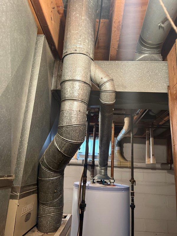 # HVAC Estimate - Replacement Summary

Conducted furnace replacement estimate for existing Lennox system installed in basement utility room. Assessed current equipment configuration including furnace unit and air handler, evaluated ductwork connections and clearances, and documented system specifications. Customer expressed interest in retrofit options with cost-effectiveness as primary consideration factor.

# Detailed Job Description

Performed comprehensive estimate assessment for furnace replacement in residential basement mechanical room. Evaluated existing Lennox HVAC system consisting of furnace unit and adjacent air handler cabinet currently installed against concrete block wall. 

Documented current system configuration including flexible black ductwork connections at supply plenum, metal trunk line distribution through exposed ceiling joists, and clearance spacing relative to adjacent water heater equipment. Assessed accessibility for replacement installation considering conc