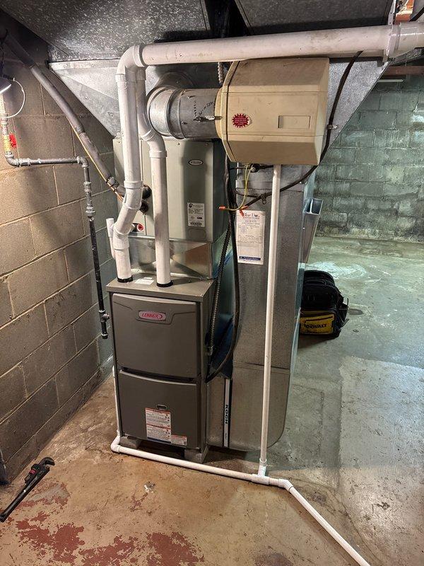 # HVAC Install - Furnace Retrofit

Completed full furnace retrofit installation in residential basement mechanical room. Installed new Lennox furnace unit with matching air handler system, positioned on concrete floor against prepared wall surface. Configured and connected white PVC venting system with proper routing through ceiling penetrations to exterior termination points per manufacturer specifications and local code requirements.

Installed new galvanized metal ductwork system including main vertical trunk line with rectangular transitions and horizontal branch connections to existing floor joist distribution network. Fabricated and secured all duct connections with proper sealing to ensure system efficiency and minimize air leakage. Connected black flexible ductwork sections between rigid components to accommodate equipment vibration and allow for thermal expansion.

Integrated copper refrigerant lines along wall with appropriate pressure gauges and service valves for system mon